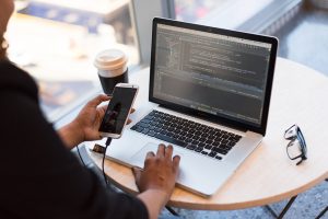 person looking at phone and at macbook pro